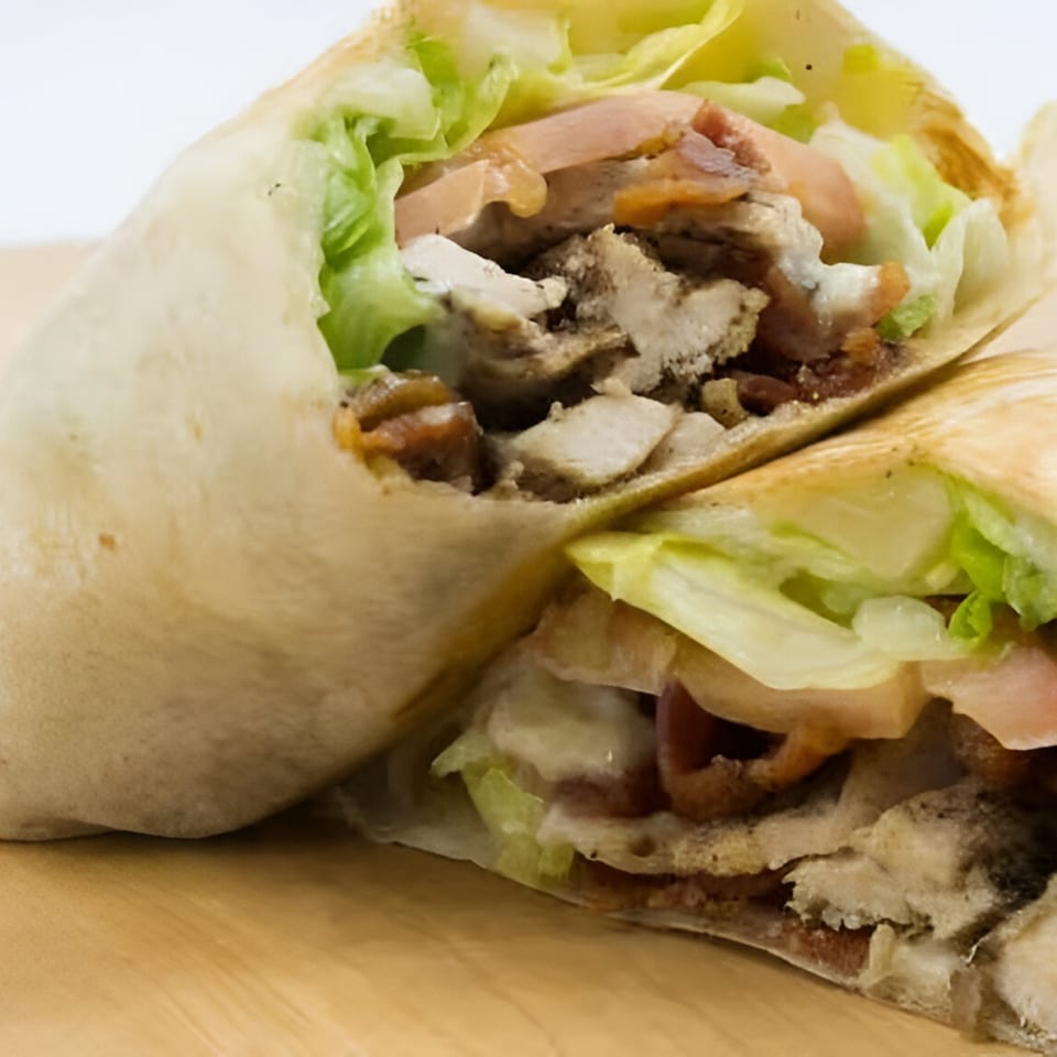 A Badda Bing's Italian Beef & Sausage wrap, cut in half, revealing meat, lettuce, and tomatoes.