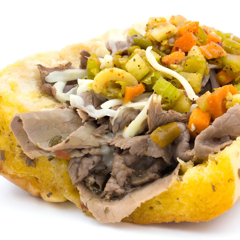 Close-up of a Badda Bing's Italian Beef sandwich with giardiniera and melted cheese.