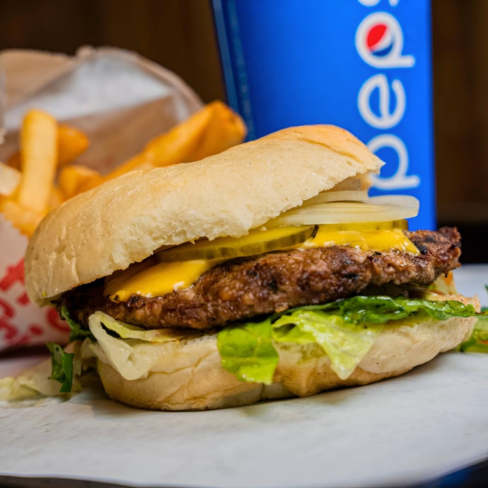 A Badda Bing's Italian Beef sandwich with cheese, pickles, onions, and lettuce, next to fries and a Pepsi.