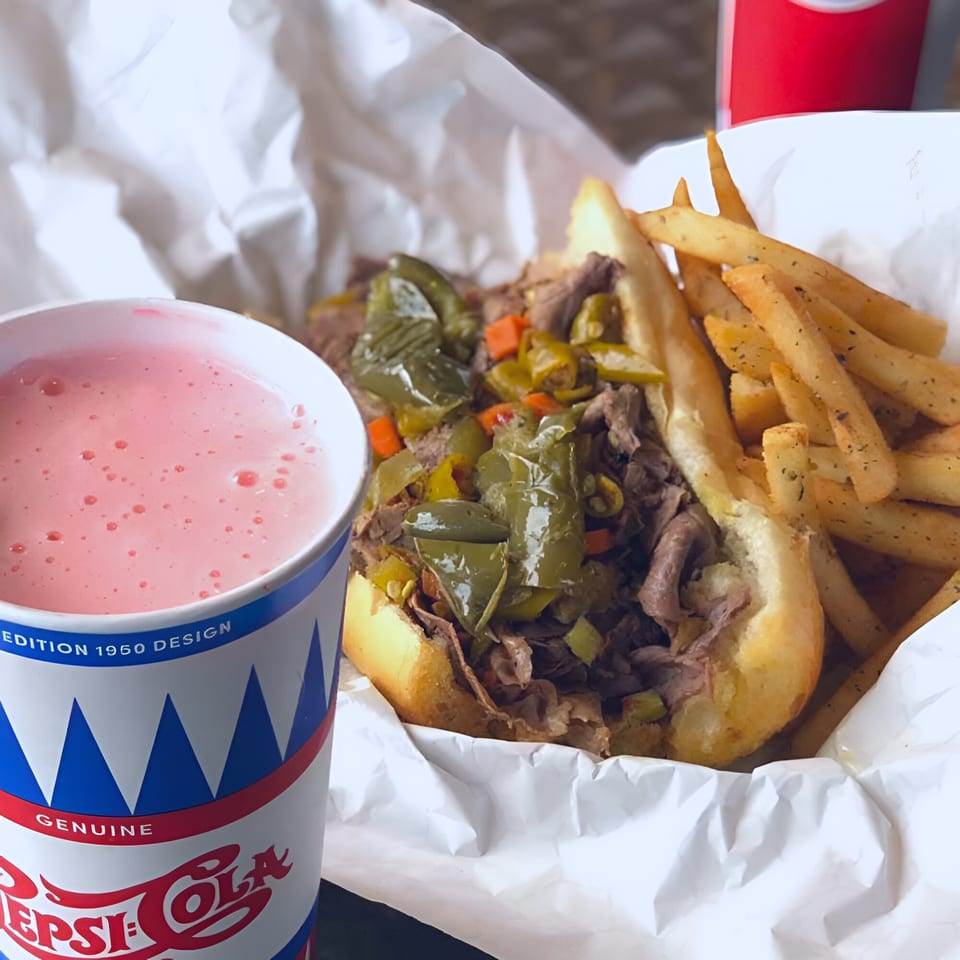 Badda Bing's Italian beef sandwich with giardiniera, fries, and a pink drink in a Pepsi cup.
